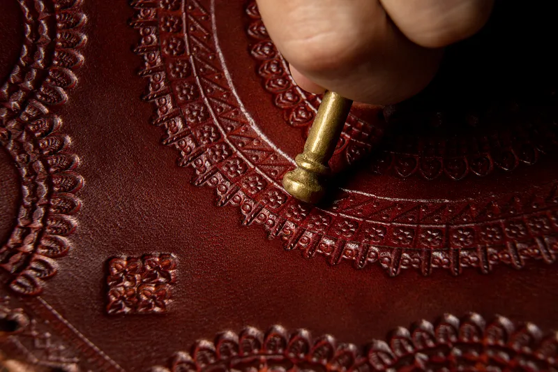 a hand holding a metal nail in a Leather Products