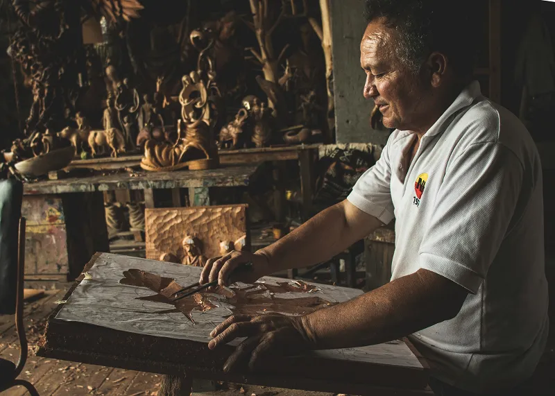 a person painting a piece of wood as moroccan products craftmanship